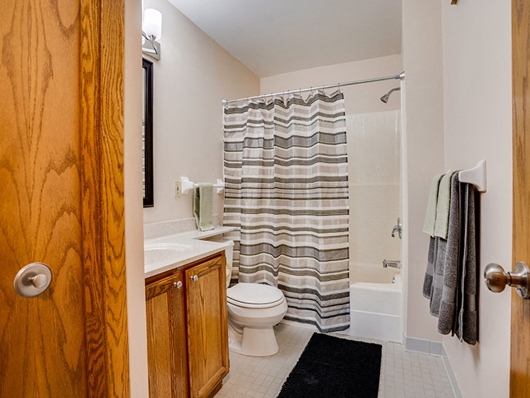 Bathroom with wooden cabnets and striped shower curtain